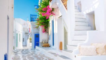 The island of Mykonos, Greece. Streets and traditional architecture. White-colored buildings and bright flowers. Travel photography.